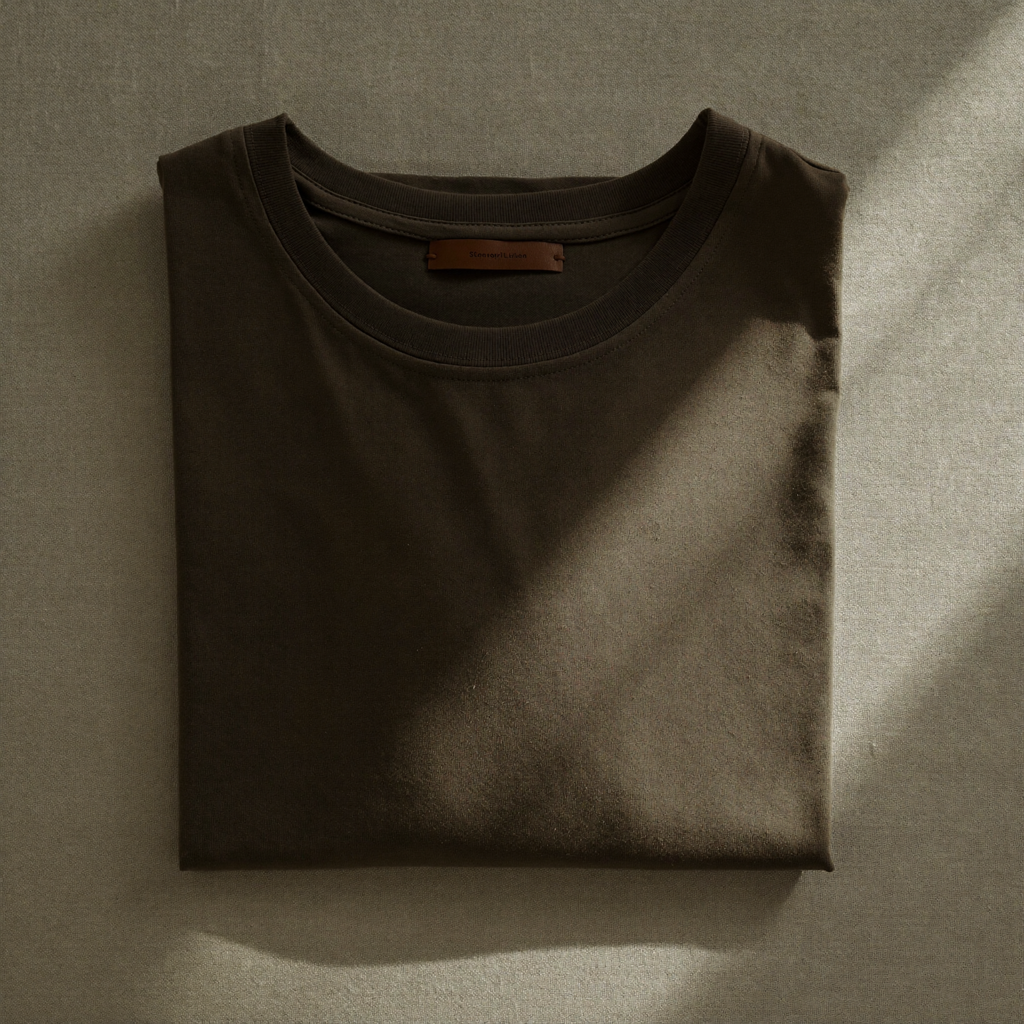 The Basic T folded flat lay on linen, camel colourway